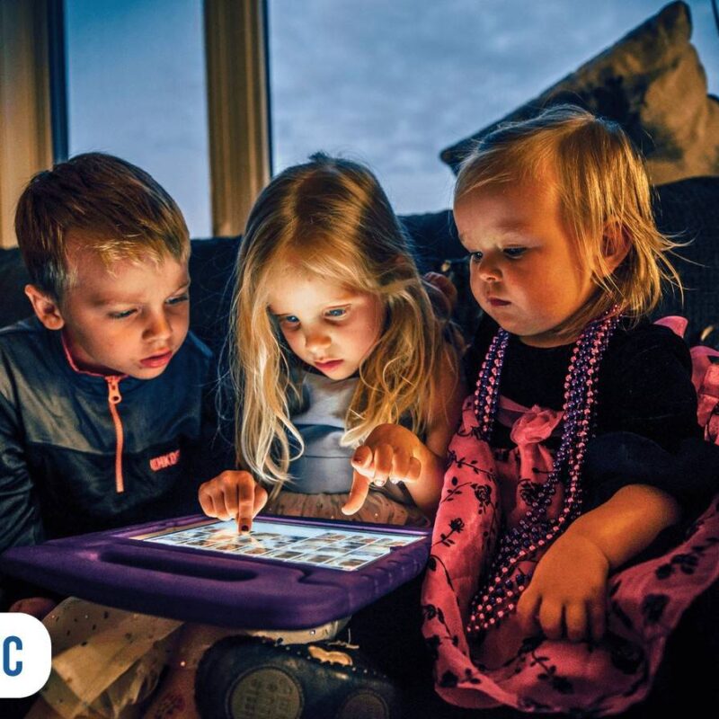 Três crianças assistindo tela de um tablet