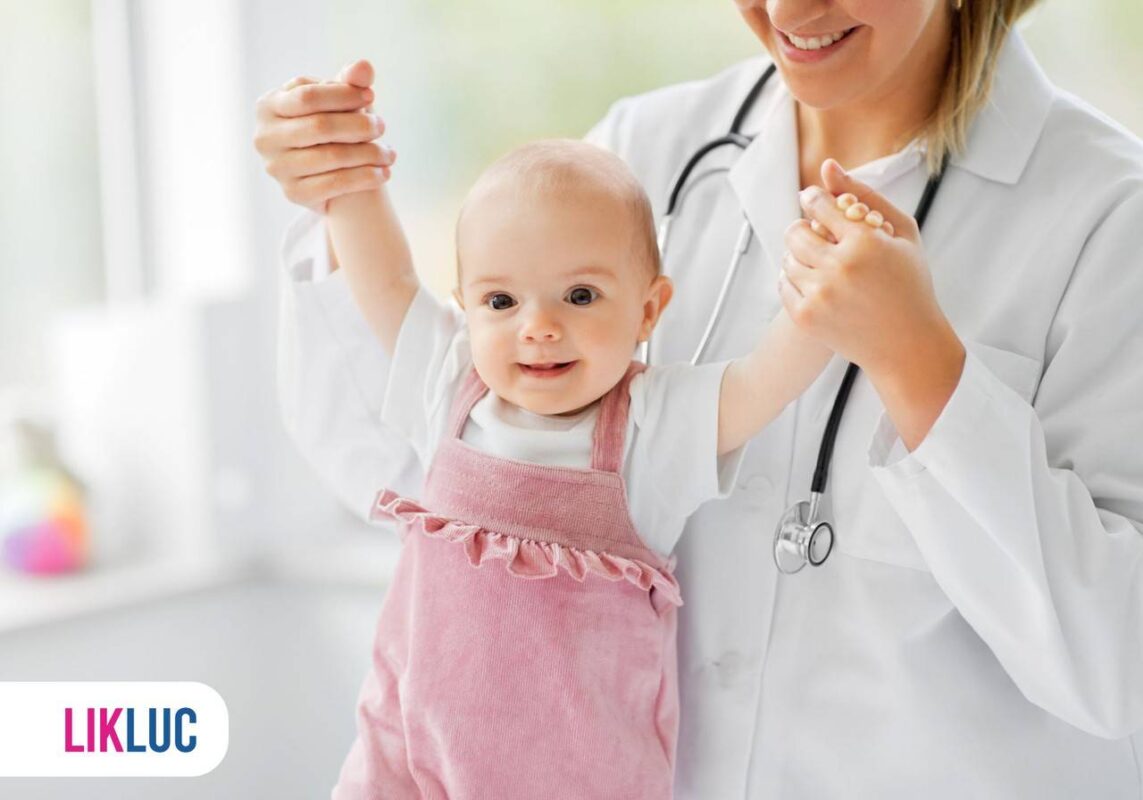 Médica pediatra segurando em mãos de bebê que está em pé