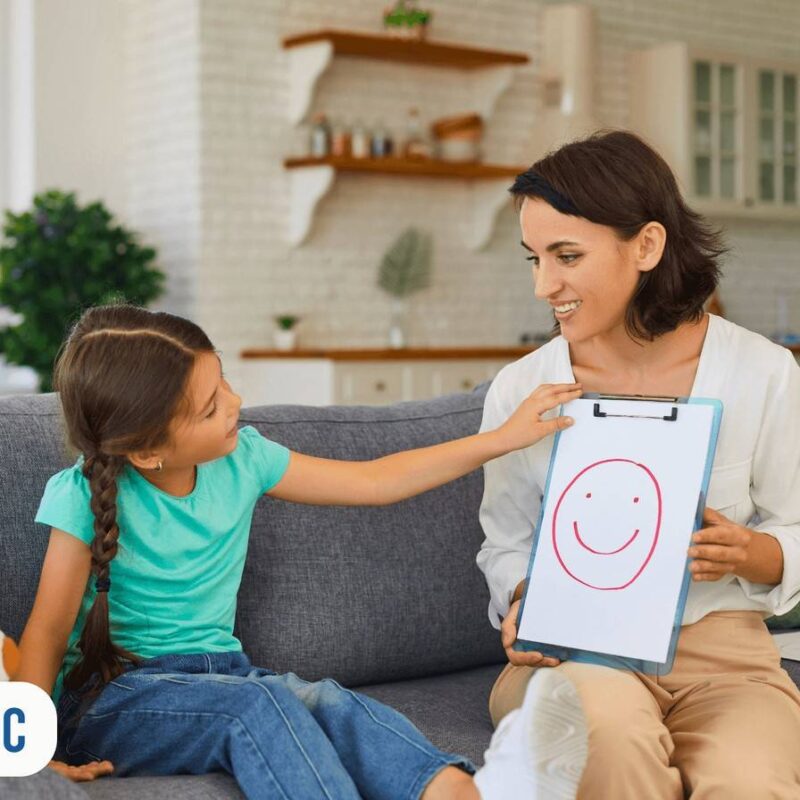Filha apontando desenho em folha de papel que mãe está segurando