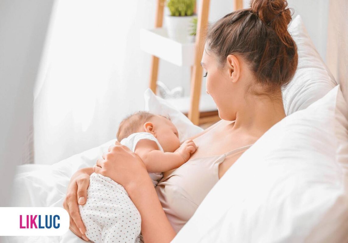 Mãe sentada em sofá amamentando bebê no colo