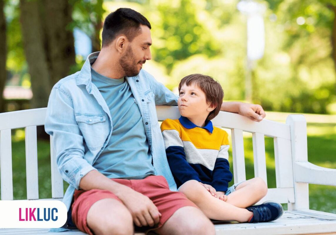 Pai e filho sentados em banco de praça e conversando entre si