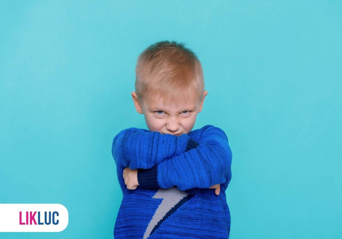 Criança com cara de brava e de braços cruzados