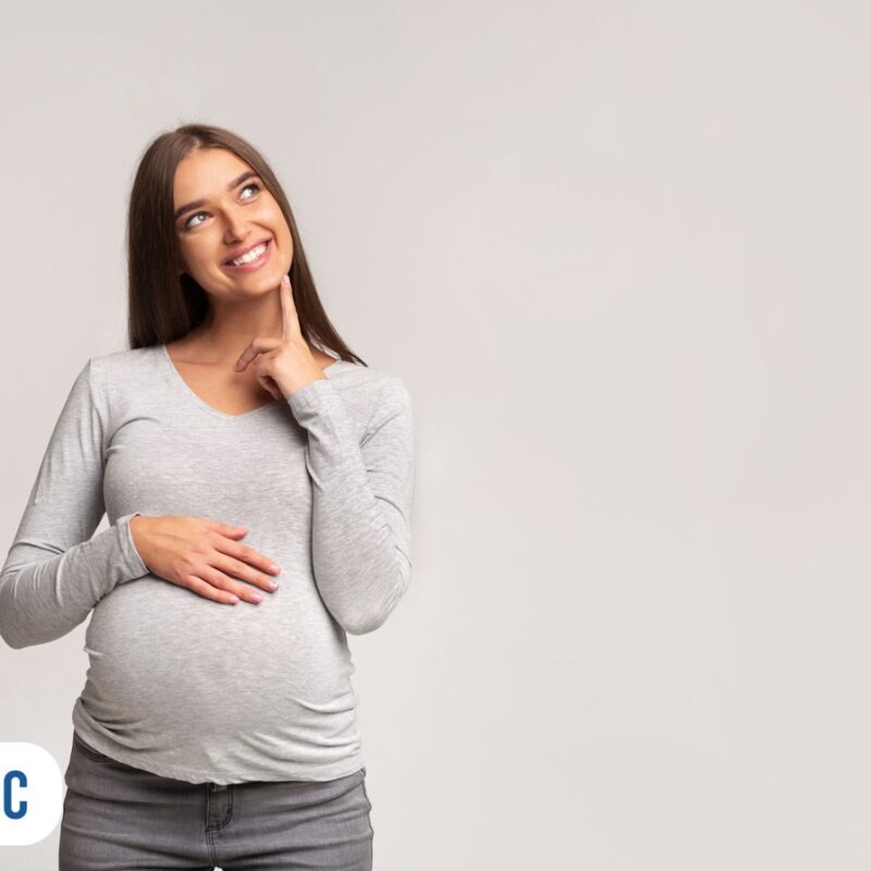 gravida feliz com mão na barriga olhando pra cima