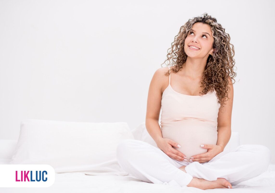 mulher grávida olhando para cima sorrindo segurando a barriga