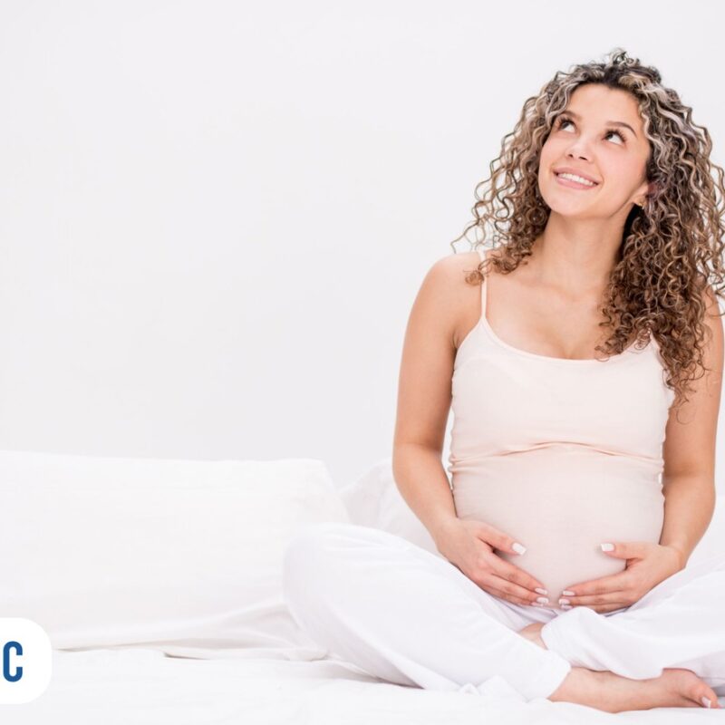 mulher grávida olhando para cima sorrindo segurando a barriga