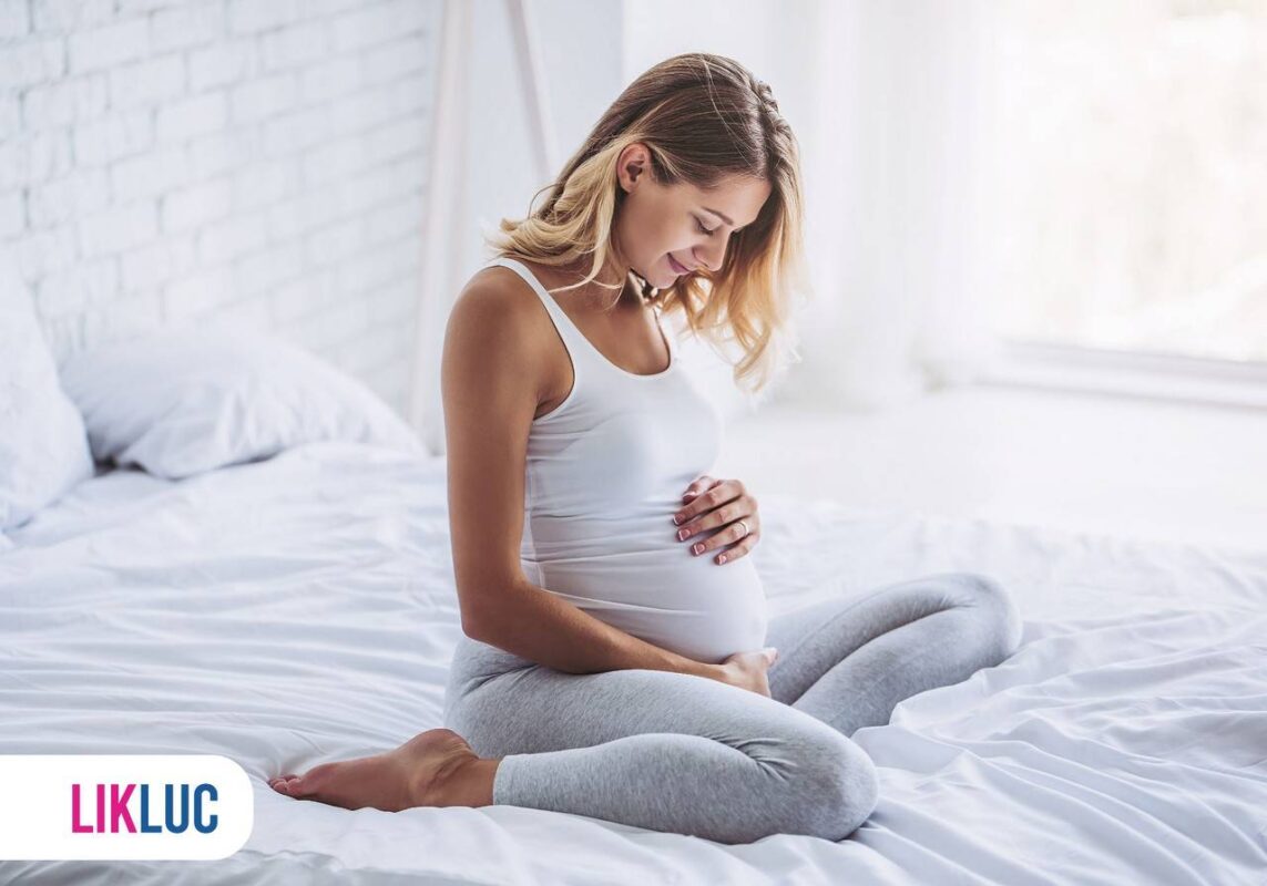 gestante feliz segurando barriga na cama
