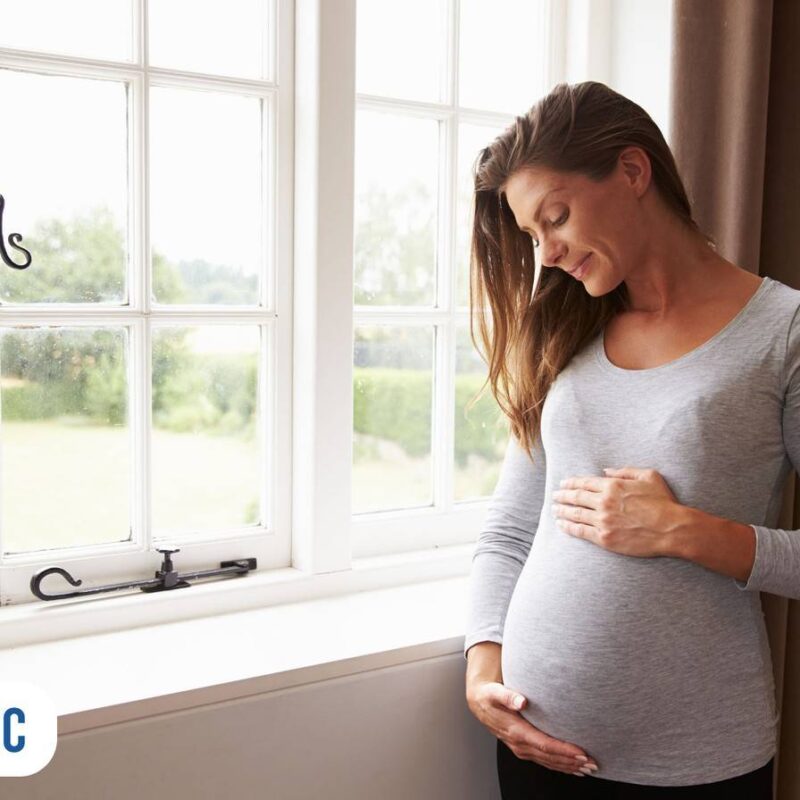 gestante feliz segurando barriga olhando para baixo