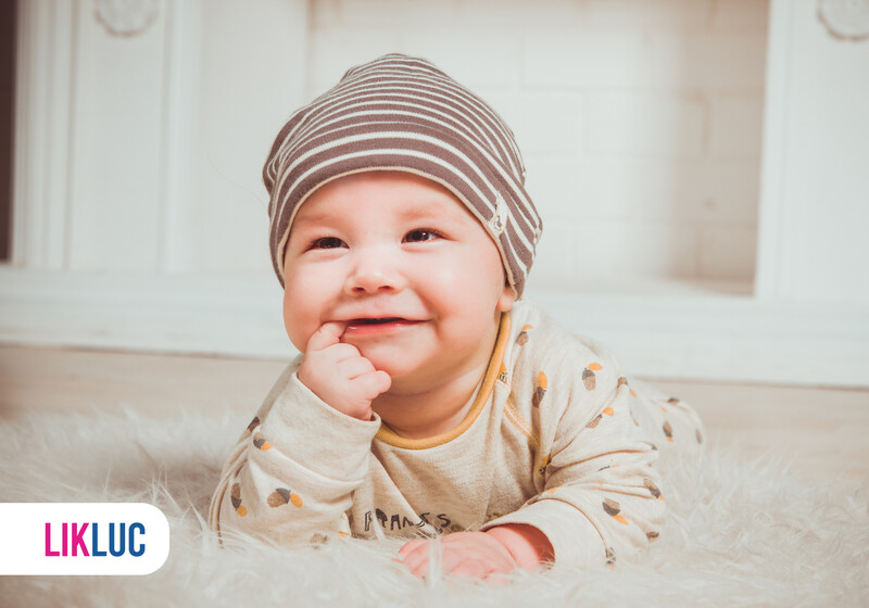 Bebê sorrindo com chapéu listrado em cenário aconchegante.