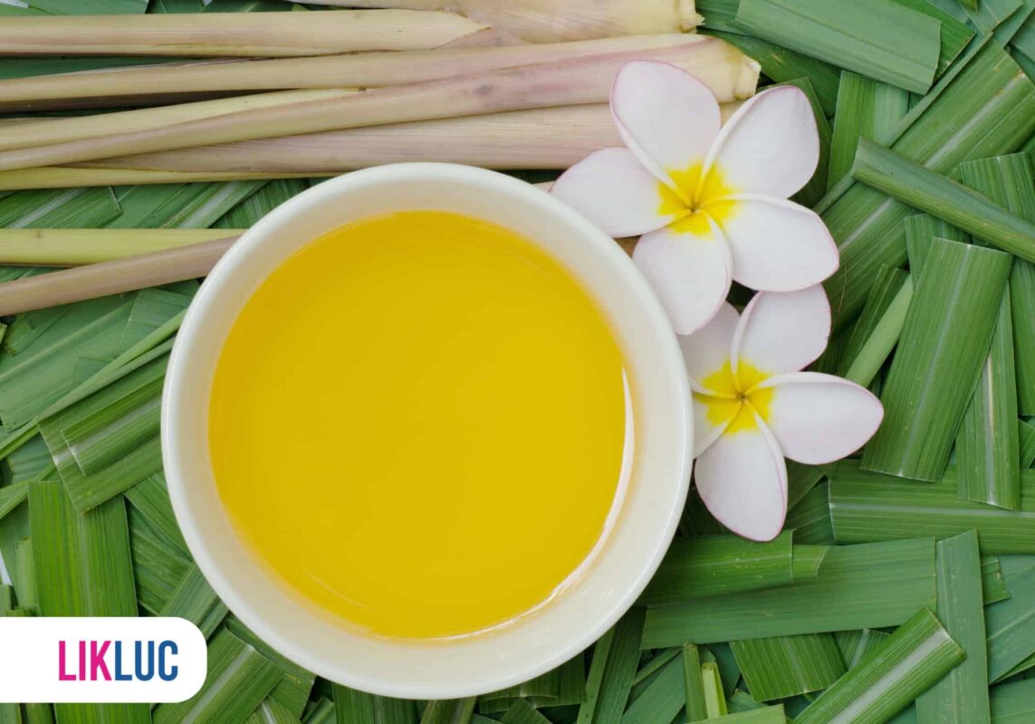 Óleo aromático de citronela ao lado de flores e folhas verdes