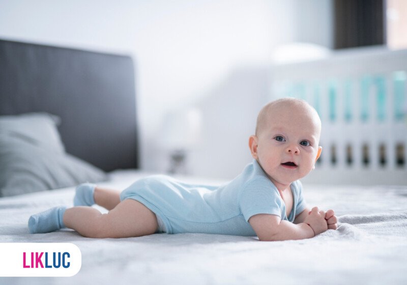 Bebê deitado de barriga para baixo em um berço.