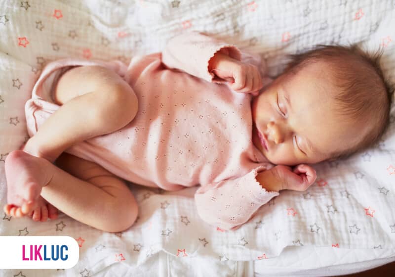 Bebê dormindo tranquilamente em roupa rosa.