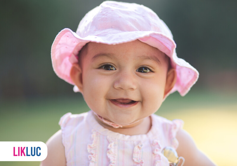 Bebê sorridente usando chapéu rosa.