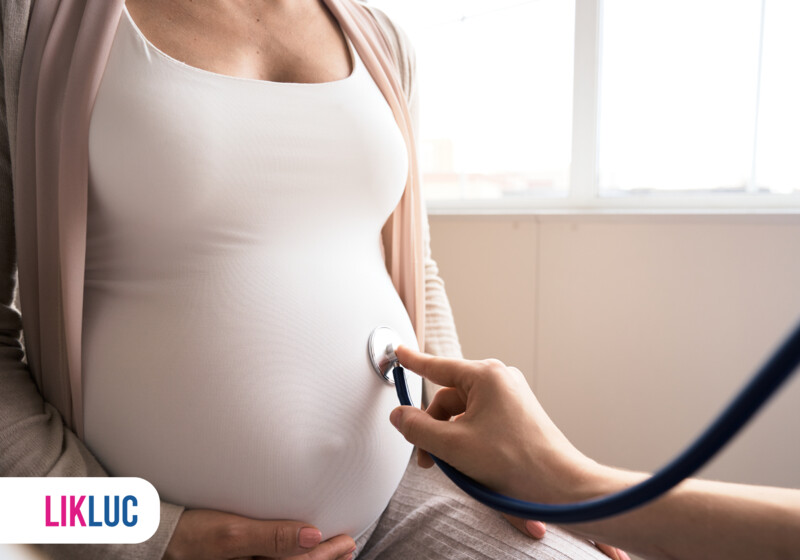 Médica auscultando barriga de gestante