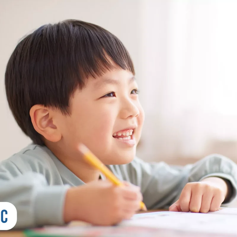 Criança japonesa desenhando com sorriso no rosto