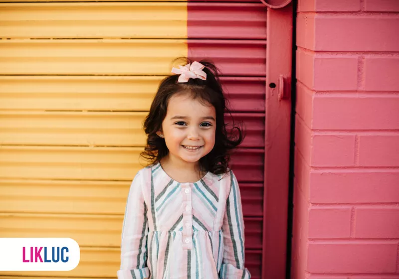 Menina sorrindo em frente a parede colorida