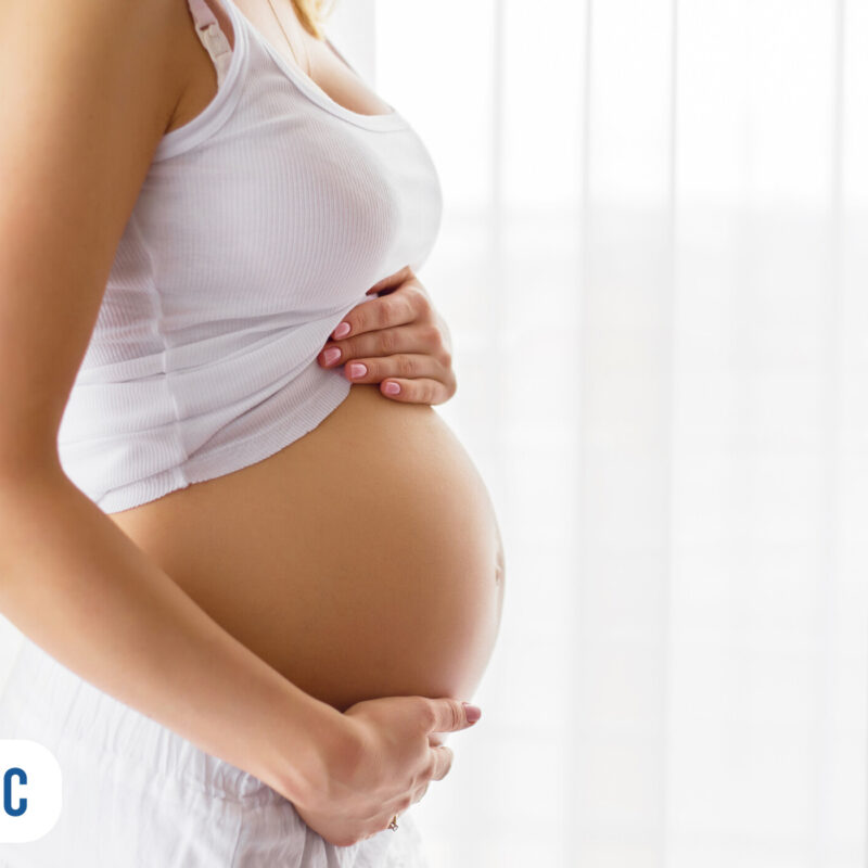 Gestante acariciando a barriga em ambiente iluminado