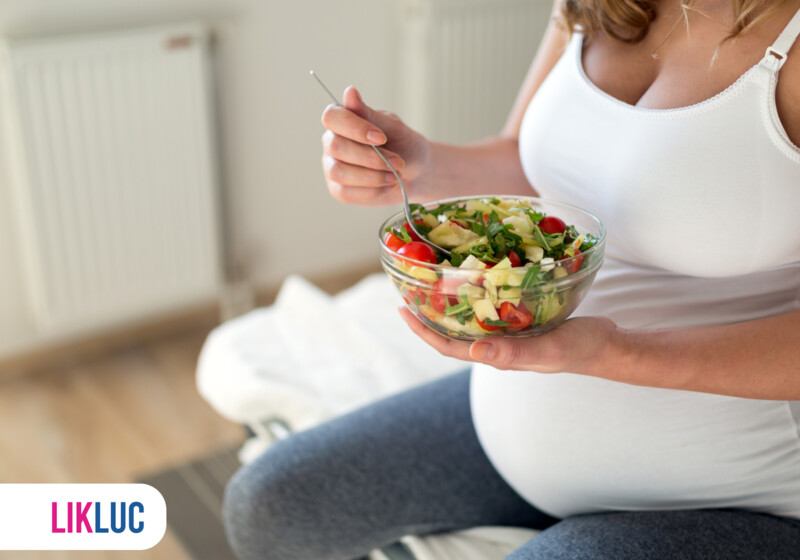 Mulher grávida segurando uma tigela de salada fresca