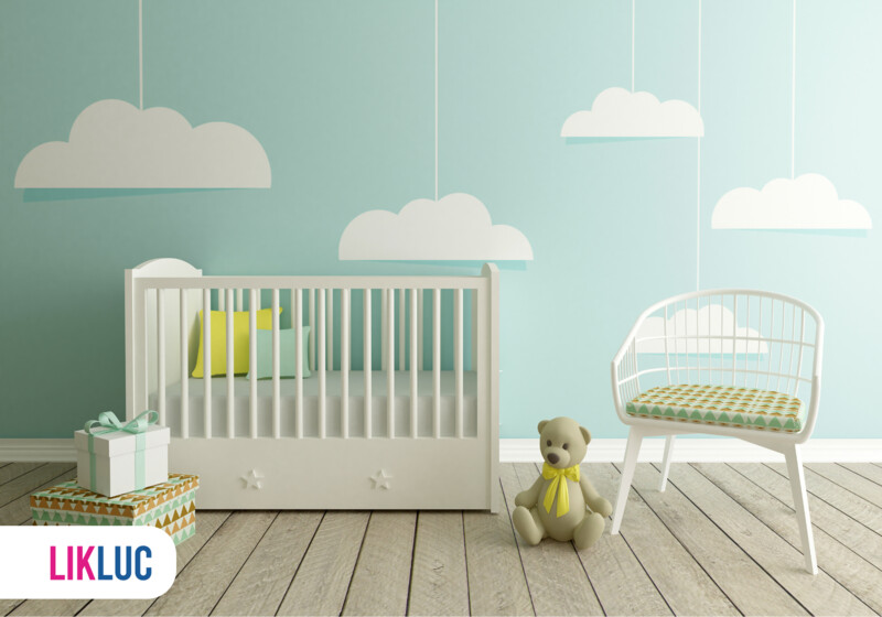 Quarto infantil com berço, cadeira e nuvens decorativas.