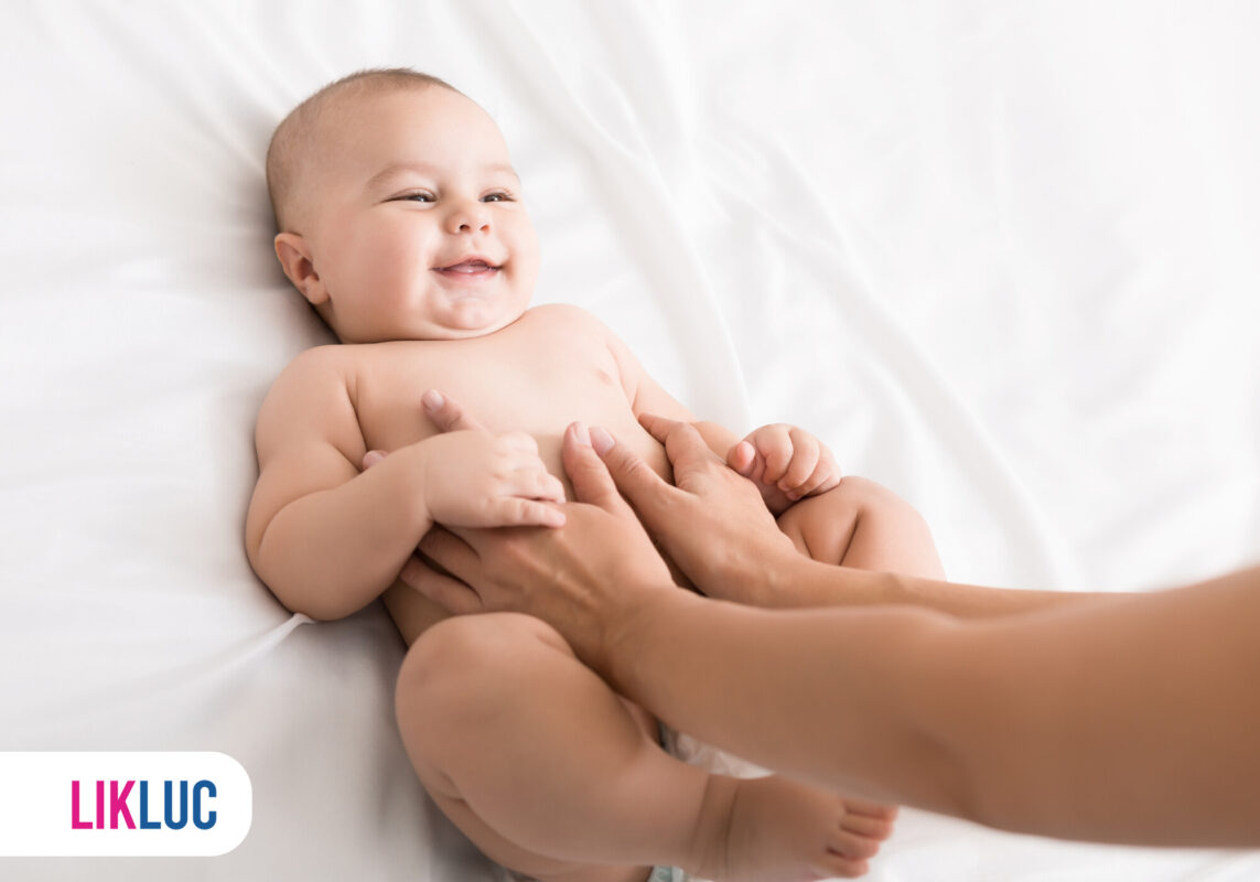 Bebê sorrindo durante carinho em cama branca