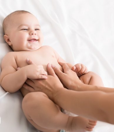 Bebê sorrindo durante carinho em cama branca