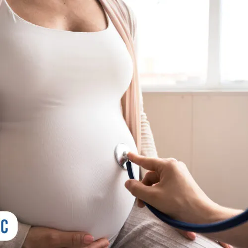 Consulta médica com gestante usando estetoscópio.