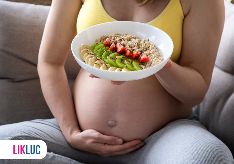 Mãe grávida segurando prato de aveia com frutas