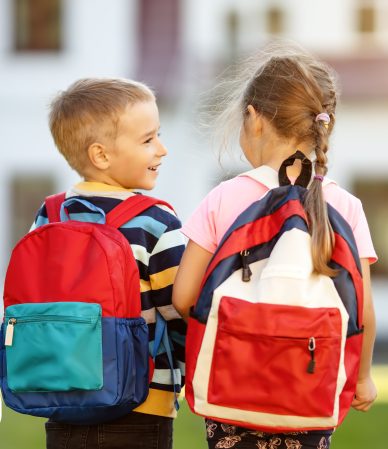 Crianças felizes com mochilas coloridas ao ar livre