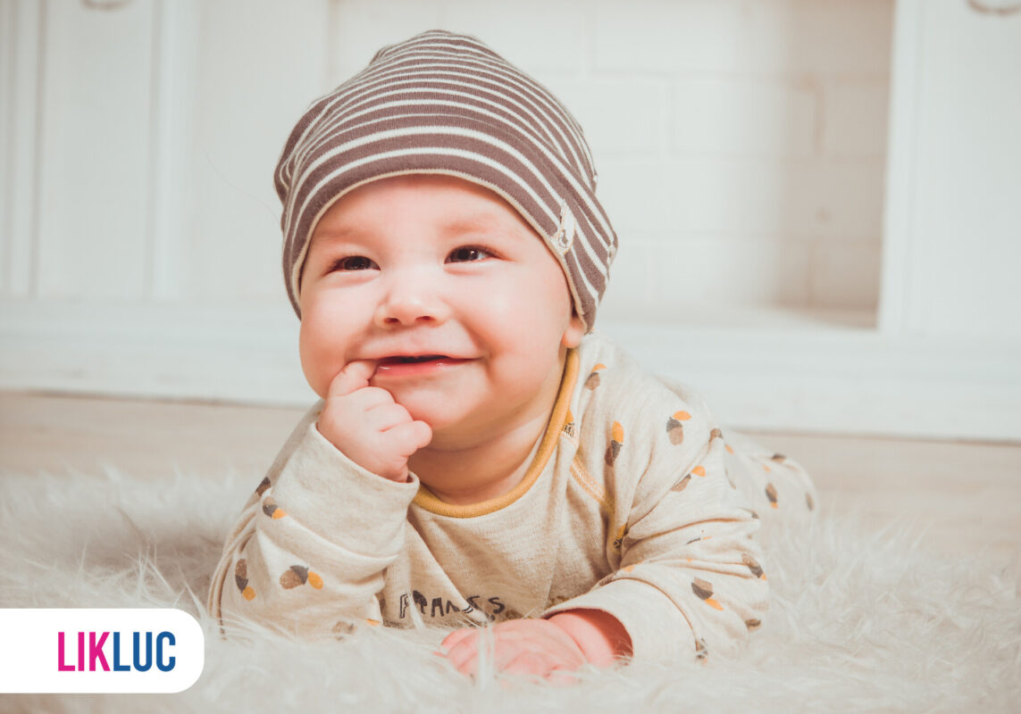 Bebê sorridente deitado com chapéu listrado