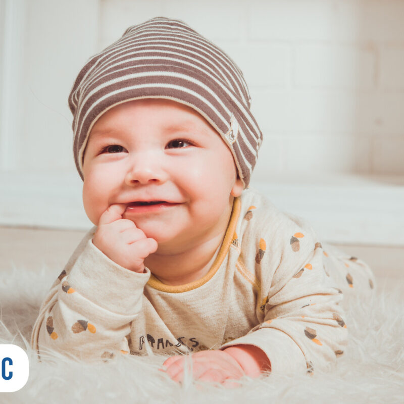 Bebê sorridente deitado com chapéu listrado