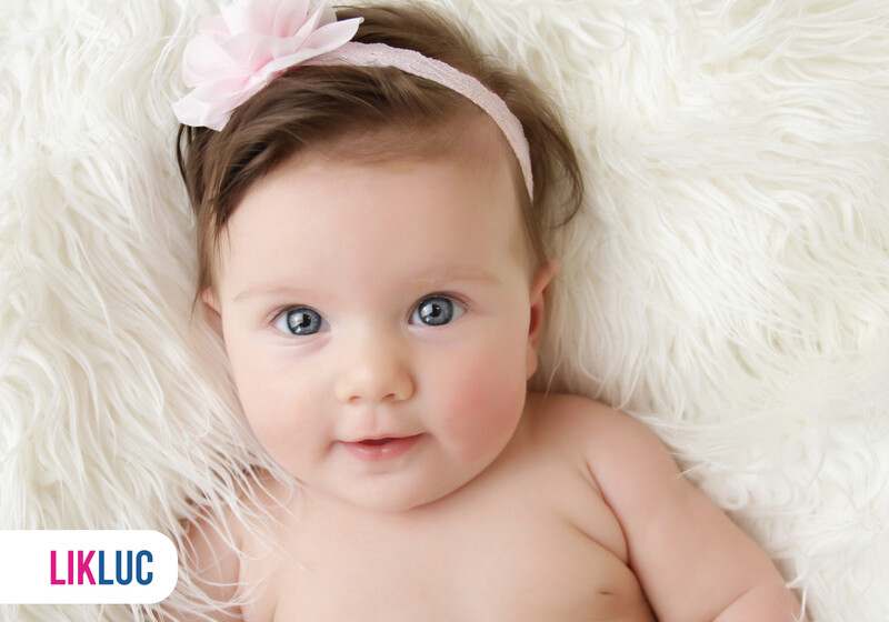 Bebê sorridente com laço rosa em fundo de pelúcia