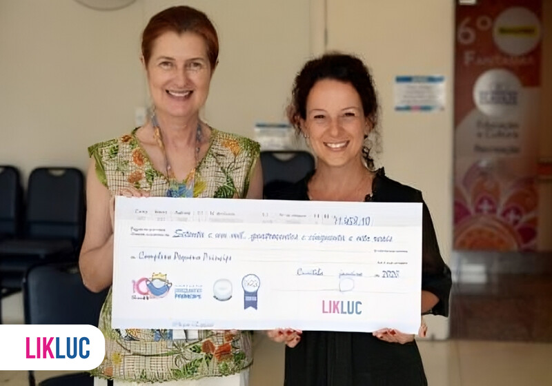 Duas mulheres segurando um grande cheque simbólico.