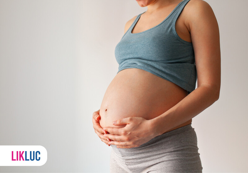 Mulher grávida segurando a barriga com carinho.