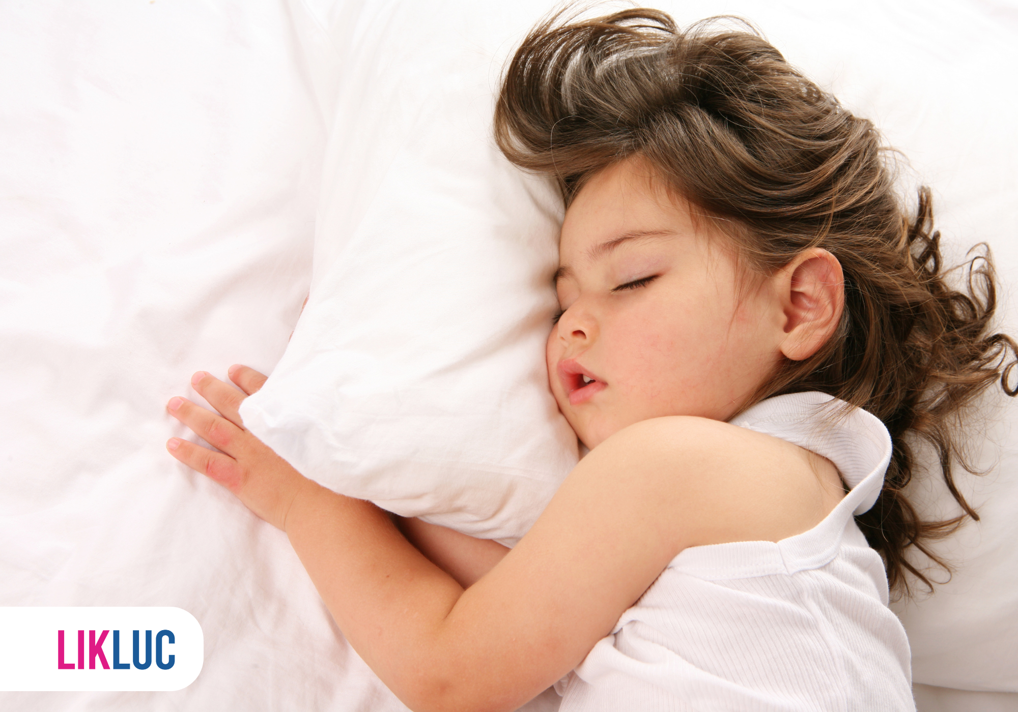 Criança dormindo confortável em lençóis brancos.