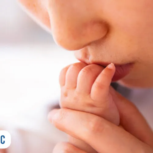 Mãe beijando a mão do seu bebê recém-nascido.