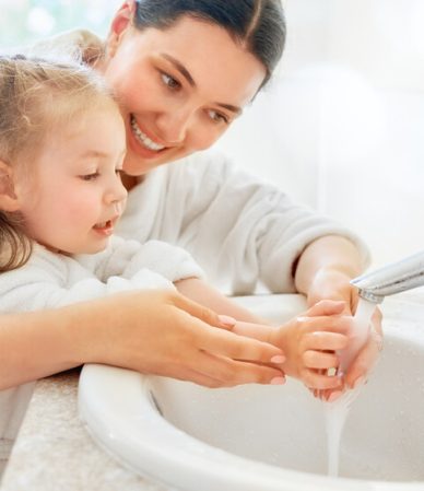 Mãe e filha lavando as mãos juntas com alegria