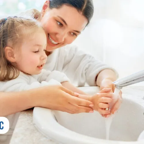 Mãe e filha lavando as mãos juntas com alegria