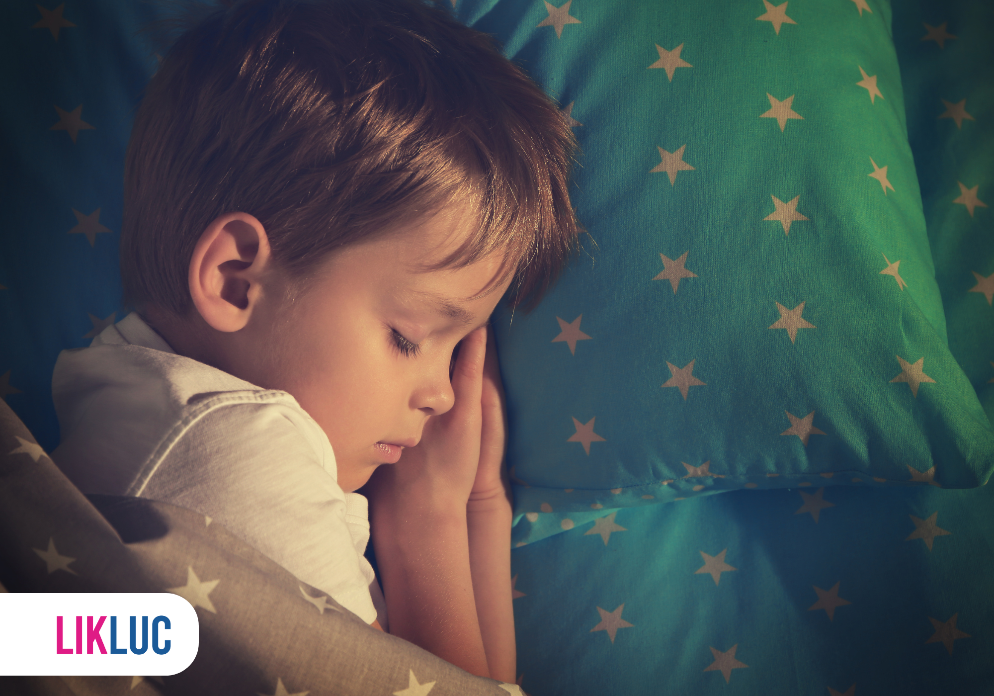 Criança dormindo sobre lençol azul com estrelas