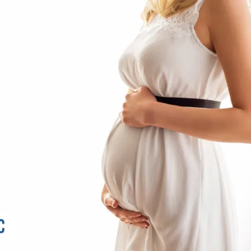 Mulher grávida em vestido claro segurando a barriga