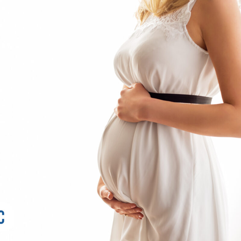 Mulher grávida em vestido claro segurando a barriga