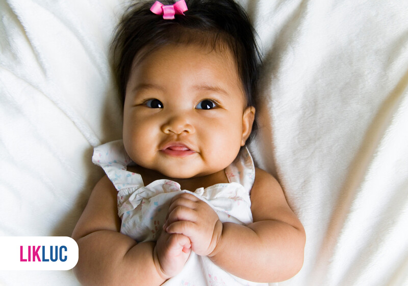 6f8faf86 bebe dormindo no berco4 Bebê sorrindo com laço rosa em fundo branco.