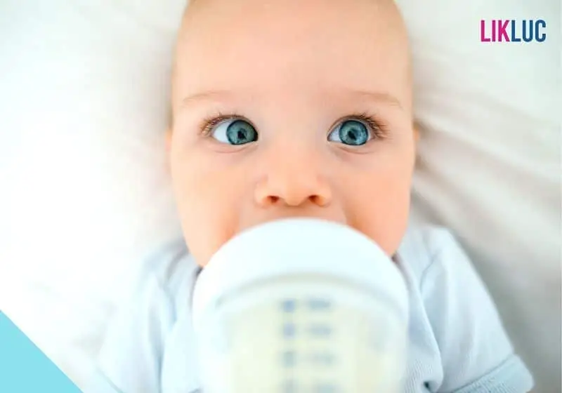 bebe com olhos azuis bebendo leite em mamadeira