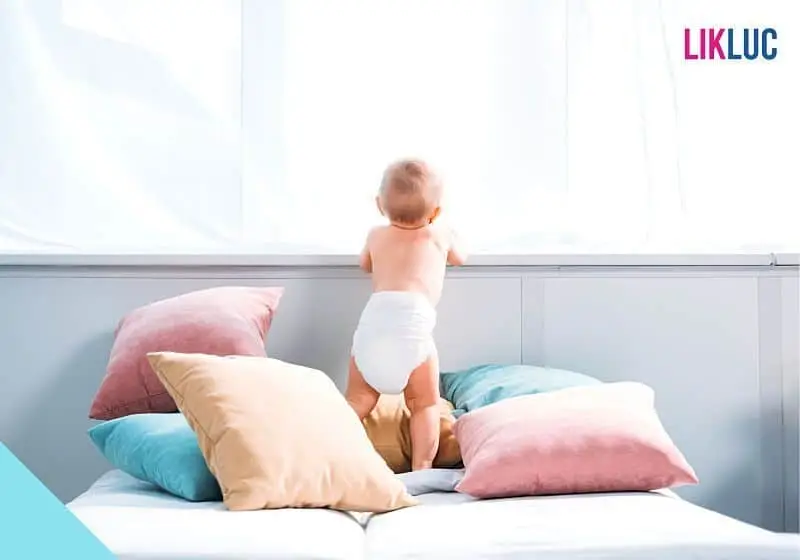 bebê em pé na cama com fundo branco