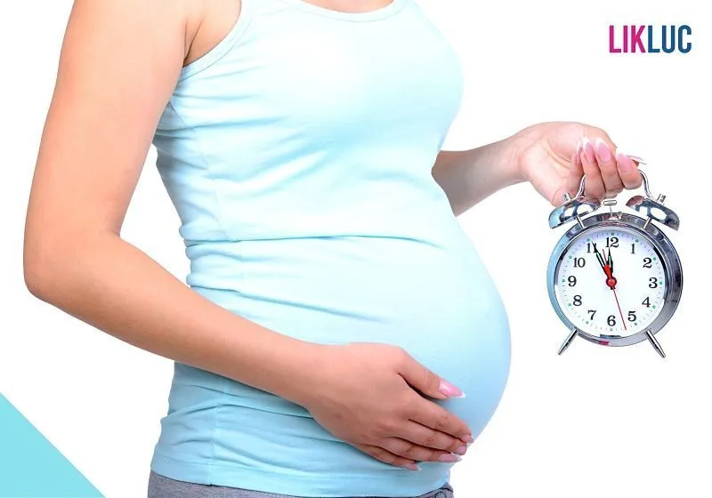 Gestante segurando relogio fundo branco Gestante segurando barriga com uma mão e relogio com outra e fundo branco