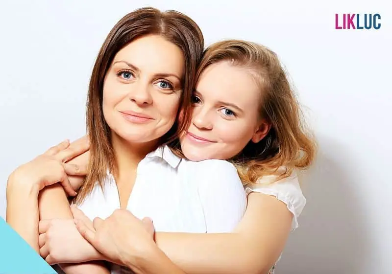 filha abraçando mae por tras com a cabeça em seu ombro e fundo branco