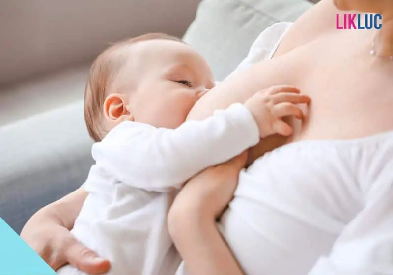bebê no colo da mãe enquanto mama opt Bebê com roupa branca, olho quase fechado e mamando no colo da mãe