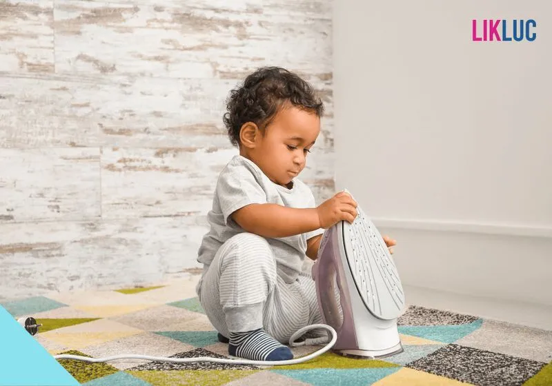 segura infantil domestica bebe agachado segurando ferro de passar desligado