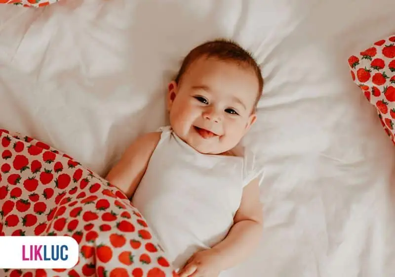 Bebê deitado e sorrindo com sua cobertinha vermelha
