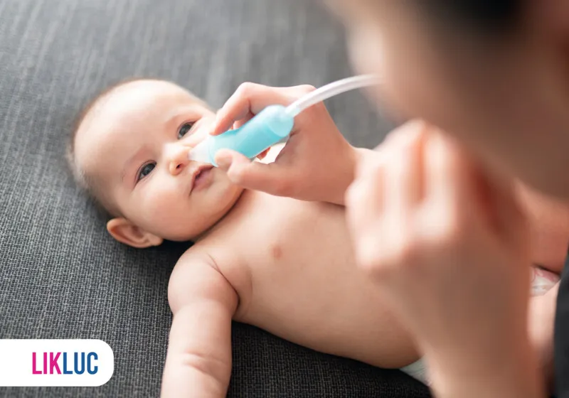 Mãe limpando o nariz de um bebê com aspirador nasal.