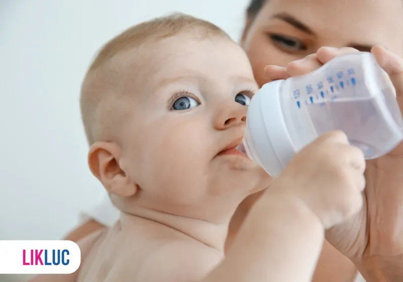 Bebê tomando leite de mamadeira com olhar curioso