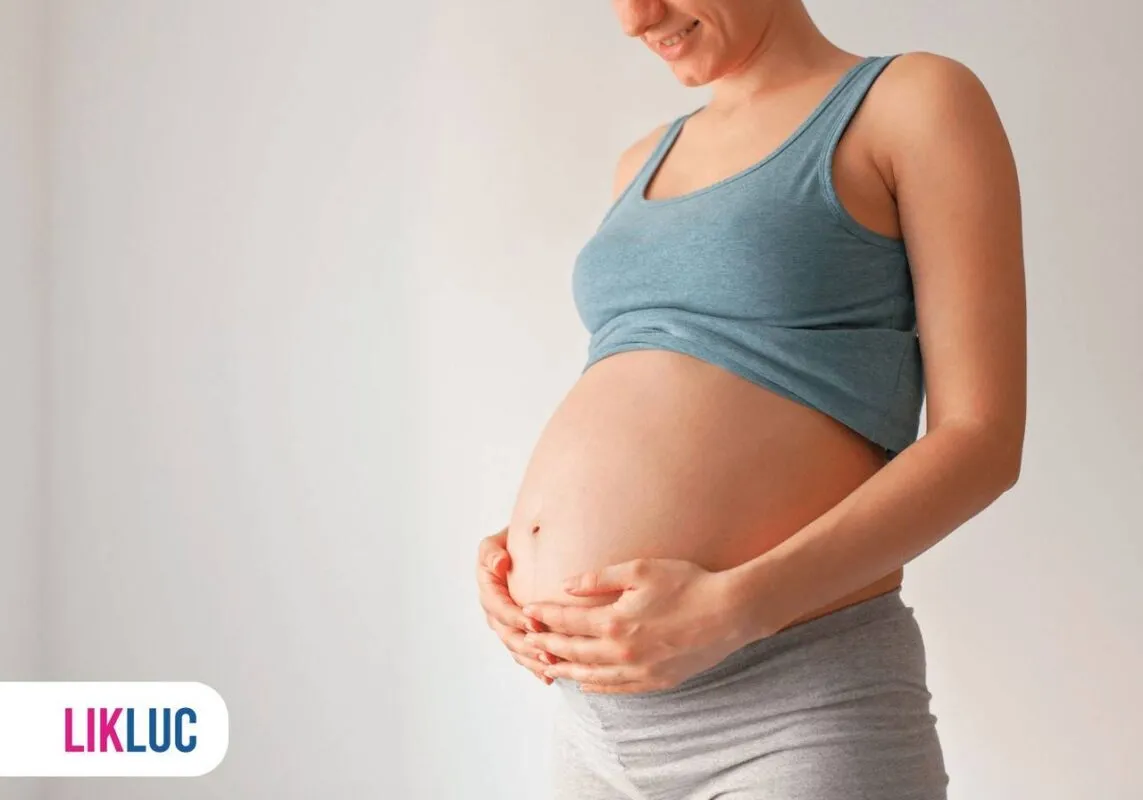 Gestante sorrindo com suas mãos na barriga